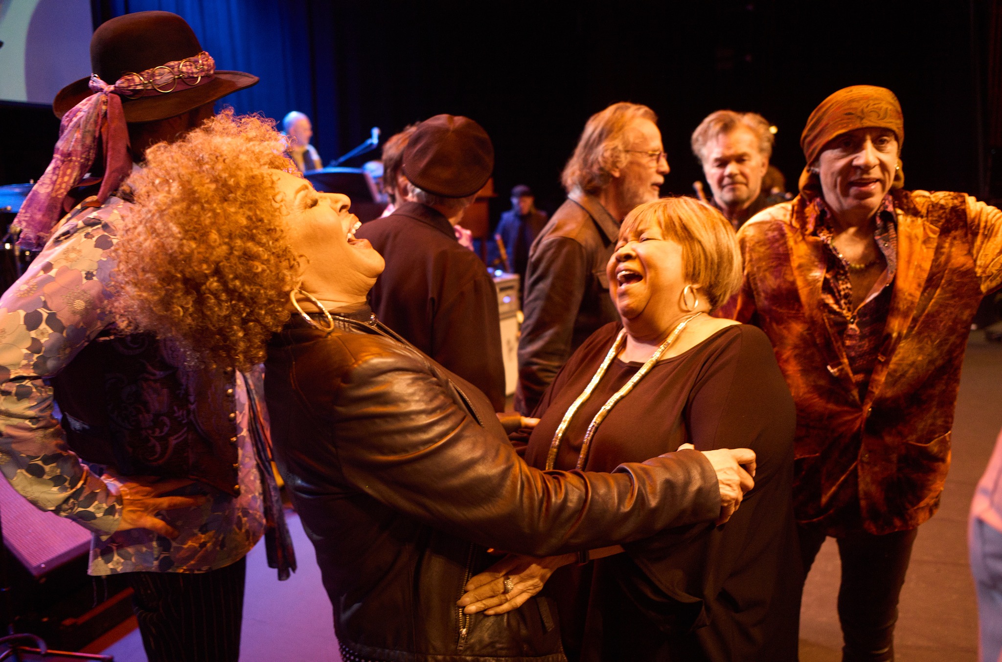 Two women laughing in a group on stage
