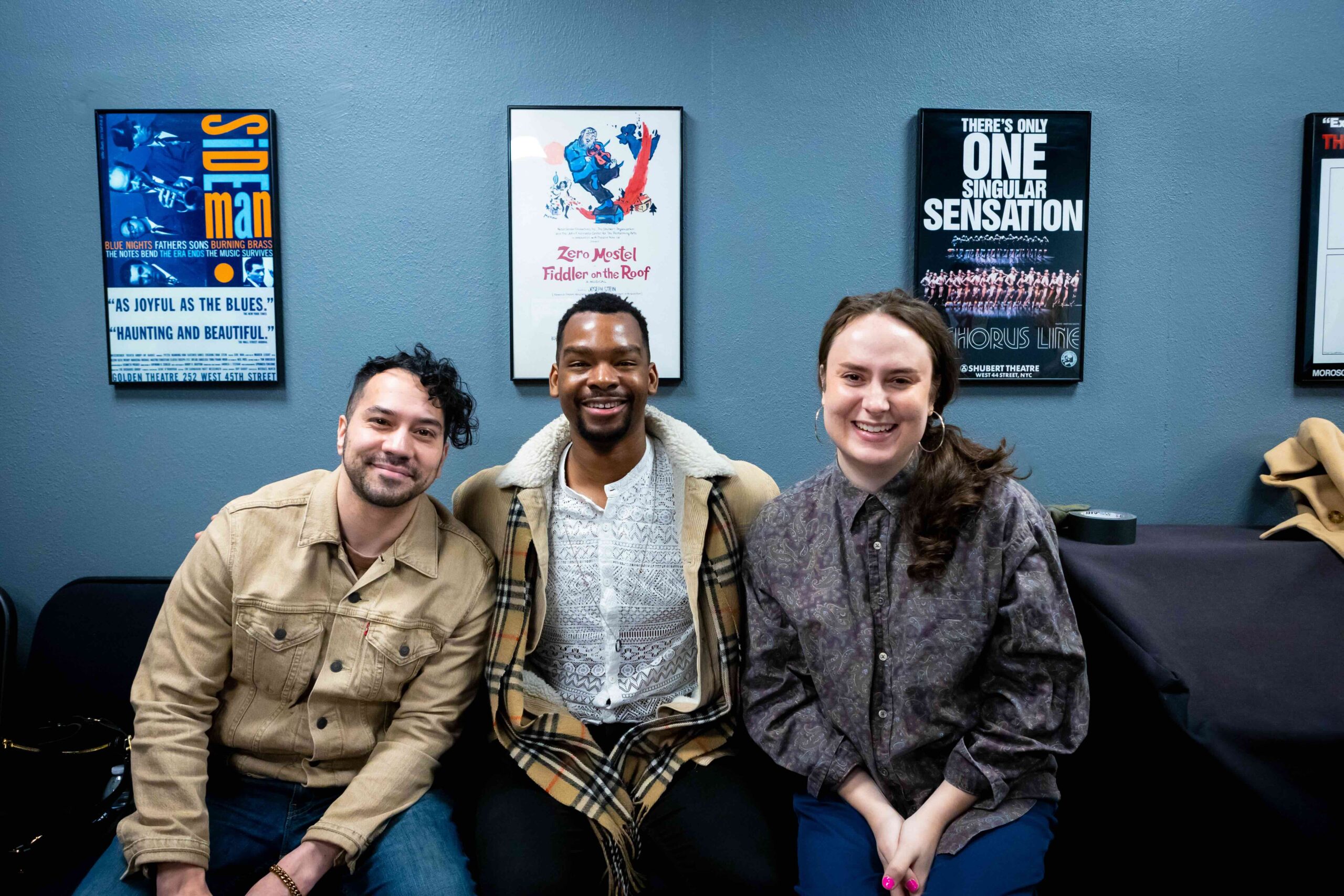 Three people in green room posing for photo