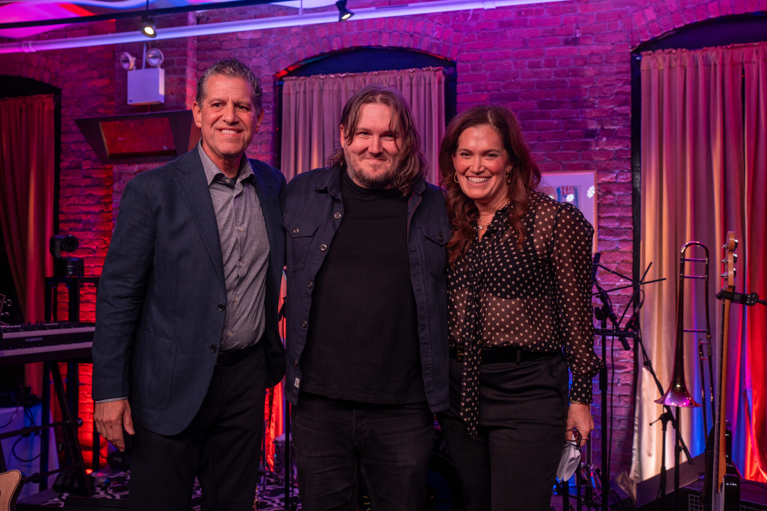 Three people posing for photo on stage
